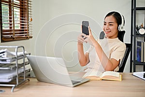 Relaxing Asian woman using smartphone and wearing headphone, listening to music