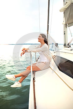 Relaxing attractive young woman on vacation sitting on yacht.