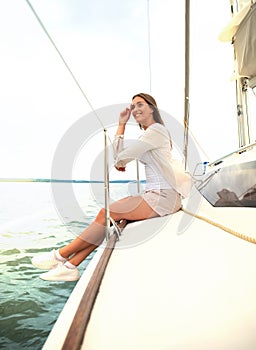 Relaxing attractive young woman on vacation sitting on yacht.