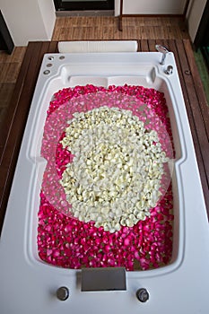 A relaxing bath with rose. bath tub with floating petals. Rose petals put in bathtub for romantic bathroom in honeymoon suit.