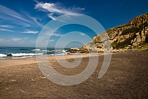 Relaxing on beautiful scenic sandy beach azkorri in springtime in blue sky