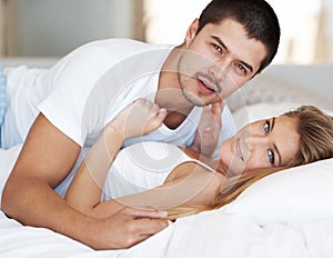 Relaxing in bed together. Affectionate young couple lying together.
