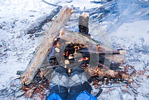 Relaxing by the campfire in winter - woman in hiking boots warmi