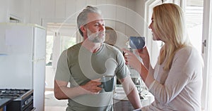 Relaxing caucasian mature couple drinking coffee and talking in kitchen