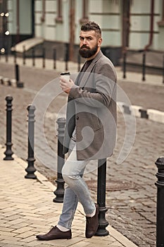 Relaxing coffee break. Hipster hold paper coffee cup and enjoy urban environment. Drink it on the go. Man bearded