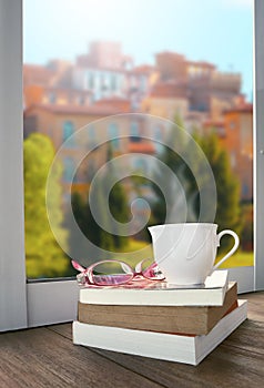 relaxing with cup of hot drink tea or coffee and book lying beside window scene of beautiful euro building style