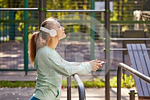 Relaxing after fitness. Young woman listening to music after training outdoors. Fitness, sport, lifestyle concept