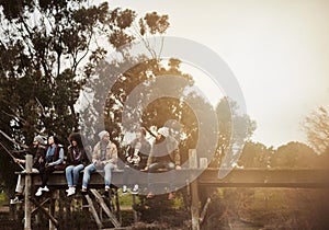 Relaxing in the great outdoors. a group of friends sitting on a pier together on a weekend breakaway.