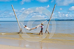 relaxing in a hammock on the beach in Phuket Thailand, couple man and woman an a luxury vacation in Thailand