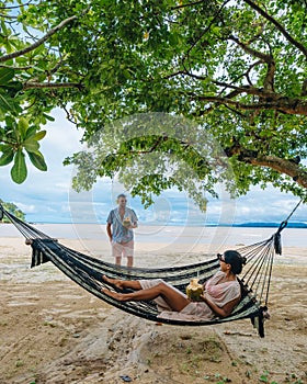 relaxing in a hammock on the beach in Phuket Thailand, couple man and woman an a luxury vacation in Thailand