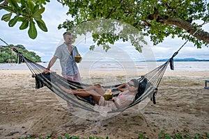 relaxing in a hammock on the beach in Phuket Thailand, couple man and woman an a luxury vacation in Thailand