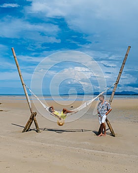 relaxing in a hammock on the beach in Phuket Thailand, couple man and woman an a luxury vacation in Thailand