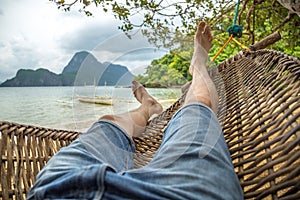 Relaxing in the hammock, nude feet close up, cloudy summer day at mountain and sea background