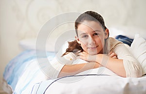 Relaxing in her room. a happy teenage girl lying on her bed.