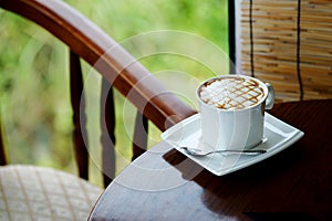 Relaxing with hot caramel cappuccino coffee Serve in white cup in garden
