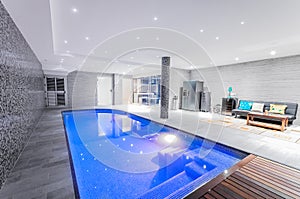 Relaxing indoor swimming pool with lighting and a corner for res