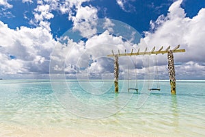 Relaxing island beach with crystal turquoise water on tropical landscape with beach swing over the water. Exotic travel vacation
