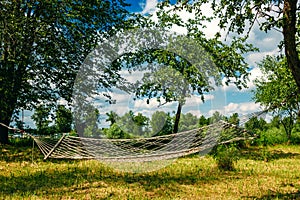 Relaxing lazy time with hammock in the green forest. Beautiful landscape with swinging hammock in the summer garden, sunny day