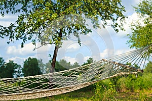 Relaxing lazy time with hammock in the green forest. Beautiful landscape with swinging hammock in the summer garden, sunny day