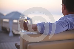 Relaxing man with glass of white wine on the beach