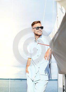 Relaxing man happily on the vacation sailboat yacht standing on a deck.