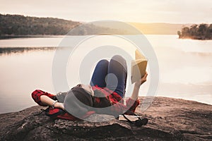 Relaxing moment Asian tourist reading a book on rock