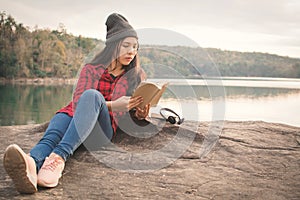 Relaxing moment Asian tourist reading a book on rock