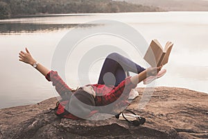 Relaxing moment Asian tourist reading a book on rock