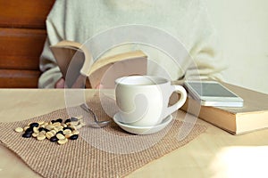 Relaxing moments, Cup of coffee and a book on wooden table in nature background, color of vintage tone and soft focus.