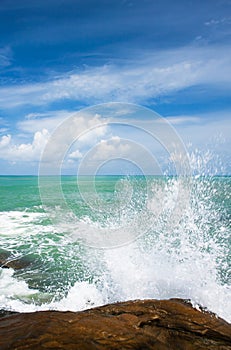 Relaxing ocean waves crashing into rocky shore on sunny summer
