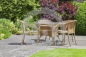 Relaxing patio wicker chairs, round table in a patio summer garden .