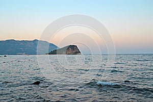 Relaxing seascape in Budva, Montenegro. Lonely island on horison under sunset sky. Time for travel, relax, leisure