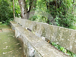 Relaxing seats, stone chairs in the park, with abundant trees and green grass.