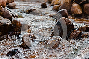 Relaxing stream flowing through stones during winter