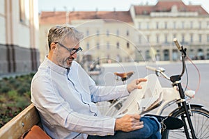 Relaxing time in city. man reading newspaper in city