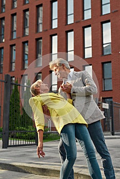 Relaxing together. Happy mature couple dancing and smiling while spending time outdoors
