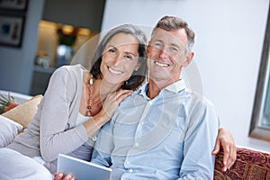 Relaxing together at home. a loving mature couple using a digital tablet at home.