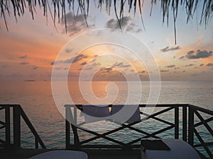 Relaxing view of open sea at dawn from Maldives resort`s water bungalow room window.