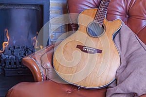 Relaxing winter hobbies. Acoustic guitar on armchair by the fire