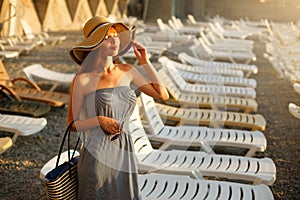 Relaxing woman enjoying the summer sun happy standing in a wide sun hat at the beach with face raised to the sunlight