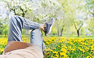 Relaxing woman lying on spring blooming meadow. Girl resting in summer park.