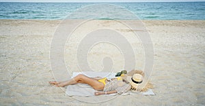 relaxing woman lying and sunbathing at beach, beach accessories and fresh fruit on blanket