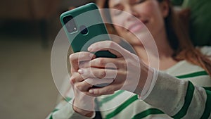 Relaxing woman typing sms holding smartphone at home couch closeup. Lady texting