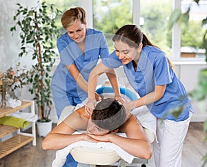 Relaxing young man getting back massage in spa center