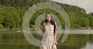 Relaxing young woman walking on wooden pier at the calm lake