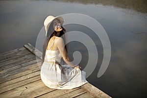 Relaxing young woman on wooden pier at the lake