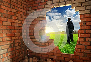 Release to freedom. Man, standing behind broken brick wall photo