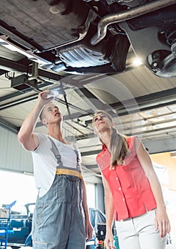 Reliable auto mechanic checking the car of a woman in a modern repair shop