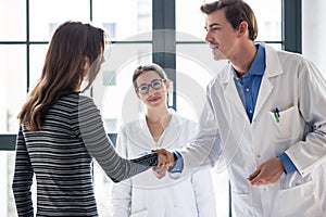 Reliable physician and female patient shaking hands before consultation