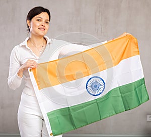 Reliant positive young woman holds big national flag of India with confident smile showing teeth
